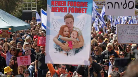 Getty Images Crowd holds poster of Bibas and two children