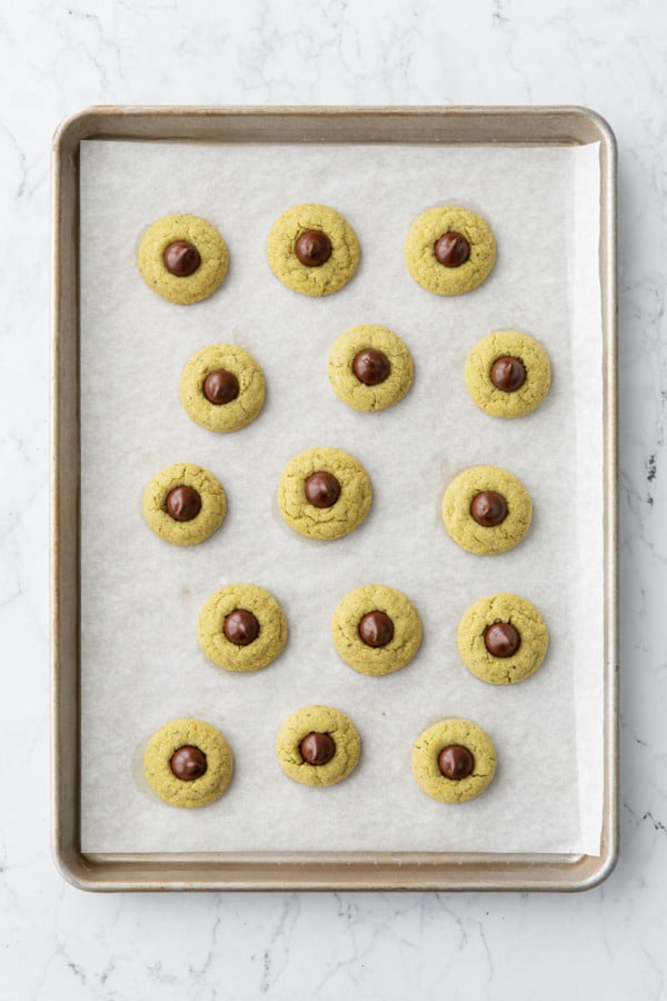 Overhead view of a full sheet of baked cookies with chocolate centers.