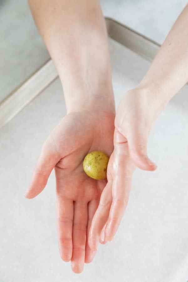 Rolling a ball of cookie dough between palms until it forms a smooth ball.