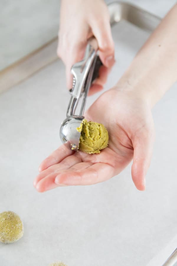 Small cookie scoop dropping a ball of dough into a hand.