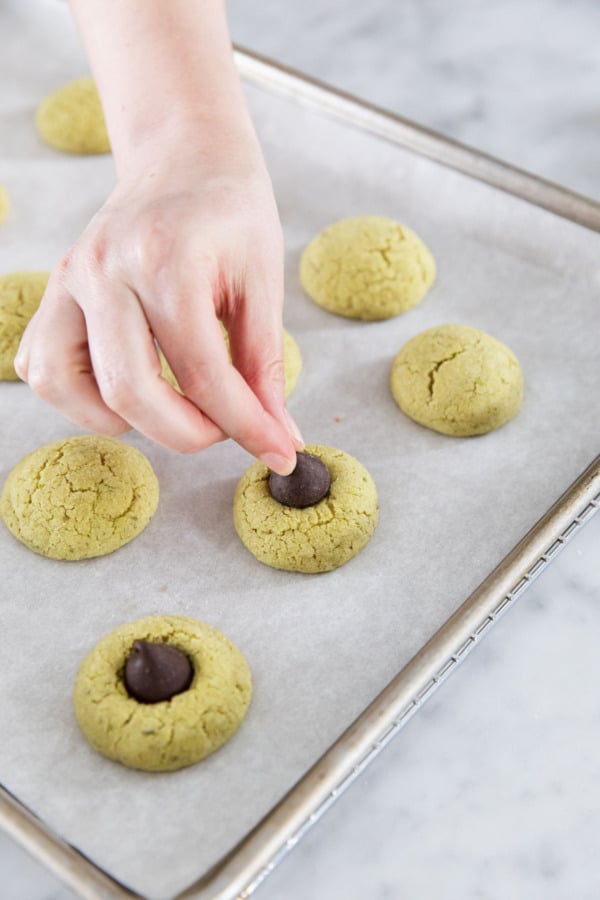 After partially baking, pressing dark chocolate kisses into the center of each cookie.