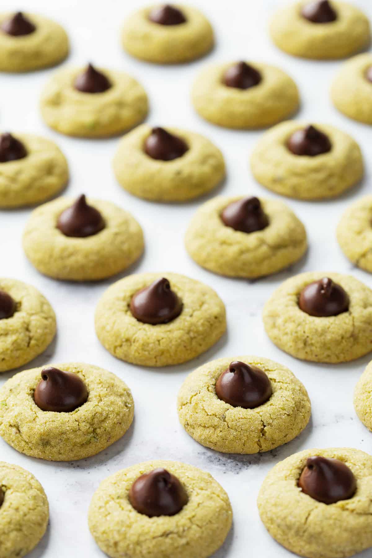 Staggered rows of Pistachio Butter Blossom Cookies on a white background.