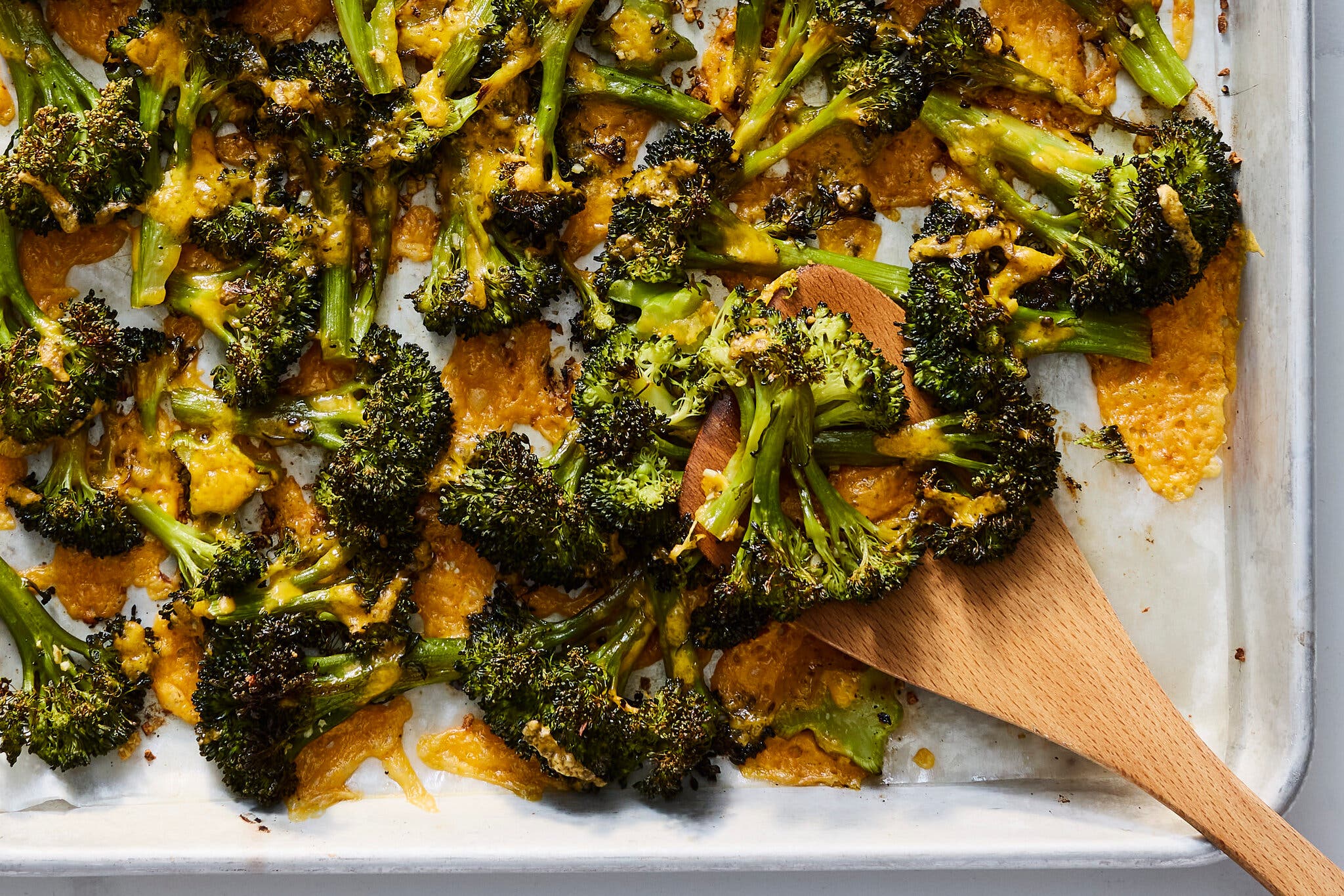 An overhead image of broccoli coated in cheese and roasted on a sheet pan. 