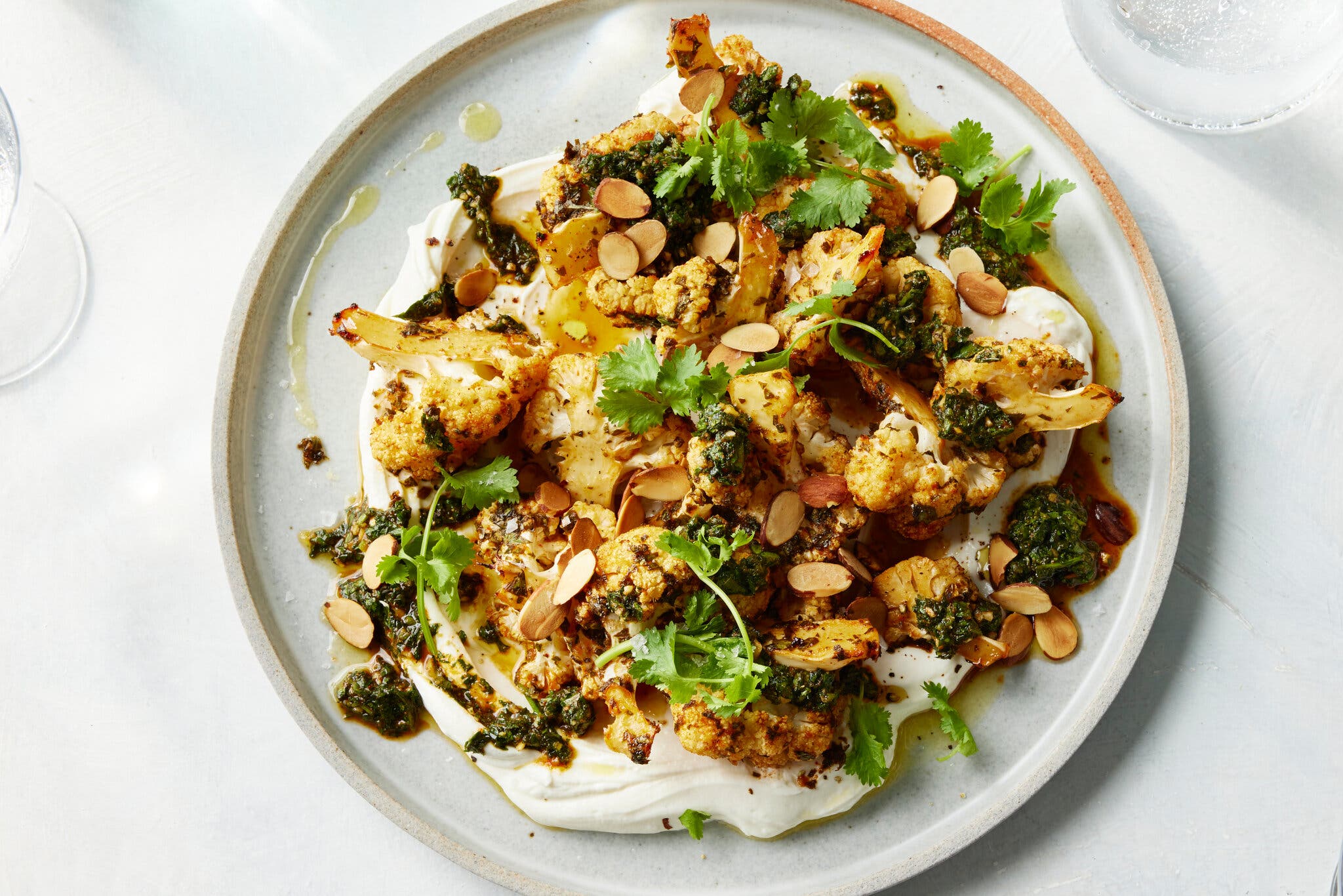 An overhead image of cauliflower florets on a bed of yogurt.