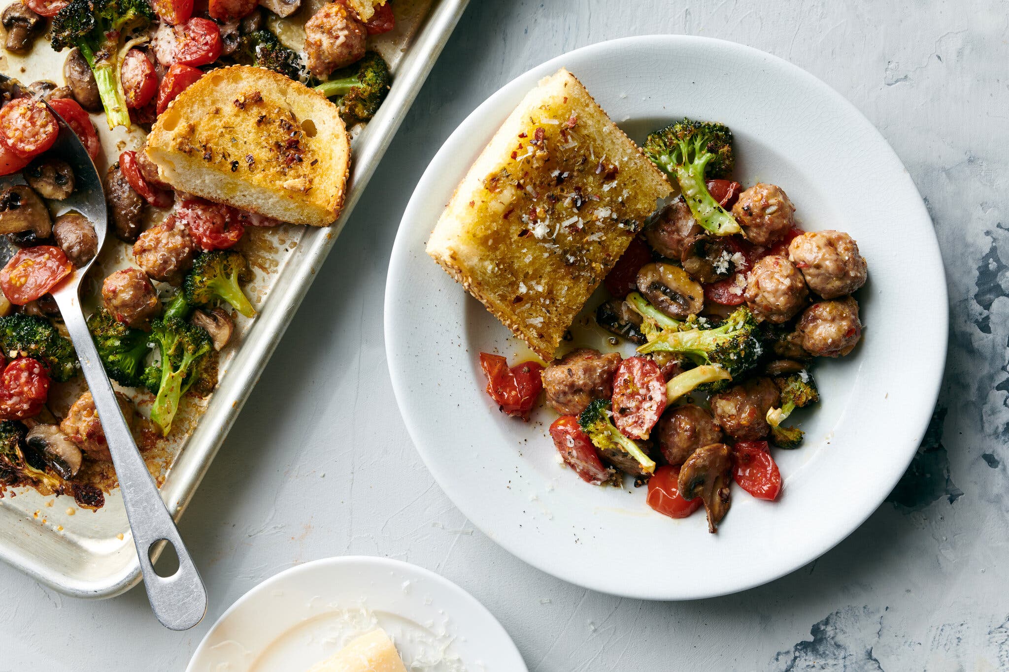 An overhead image of a bowl with tiny meatballs, broccoli florets and a piece of bread.