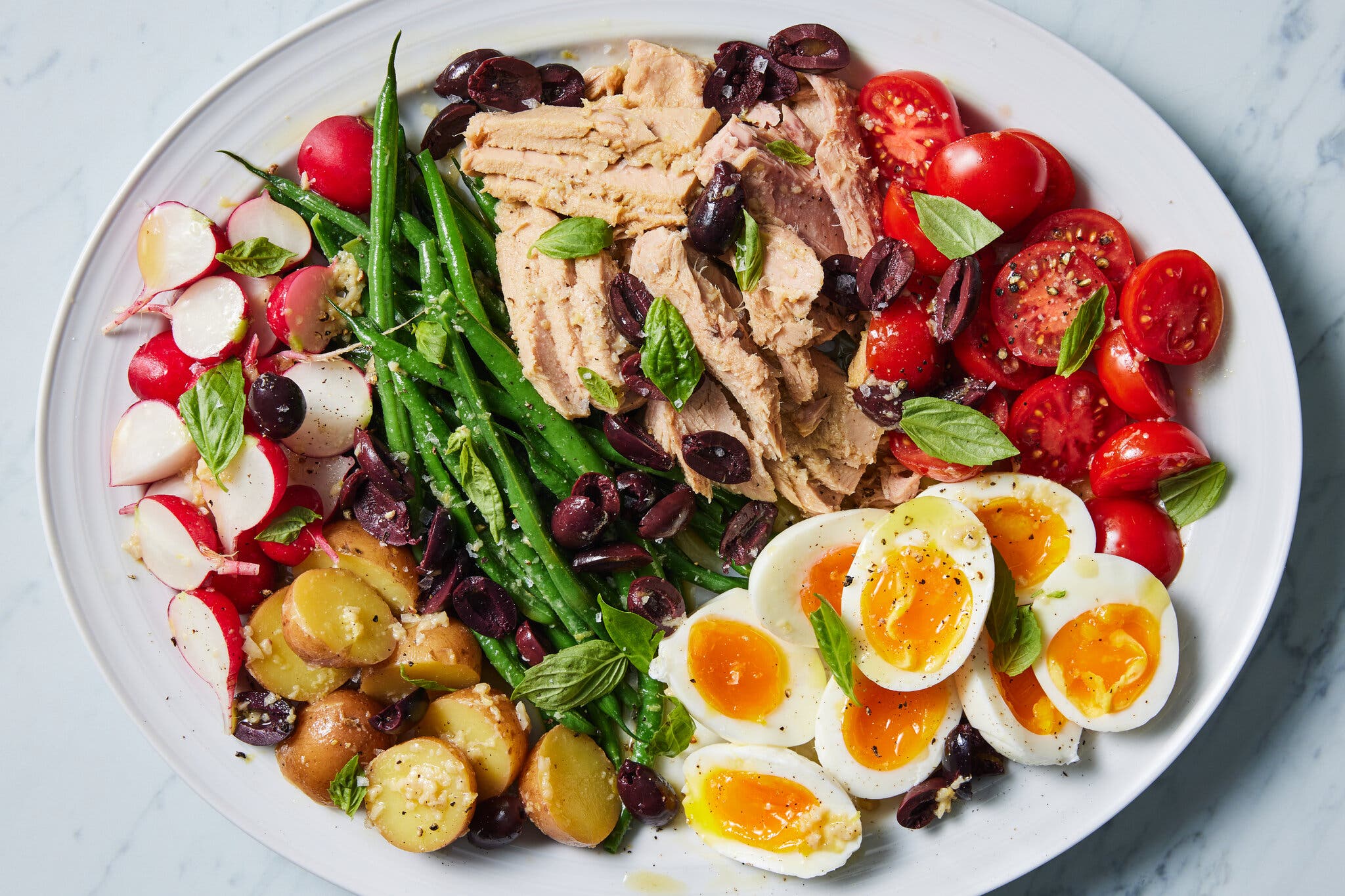 An overhead image of a niçoise salad on a white platter.