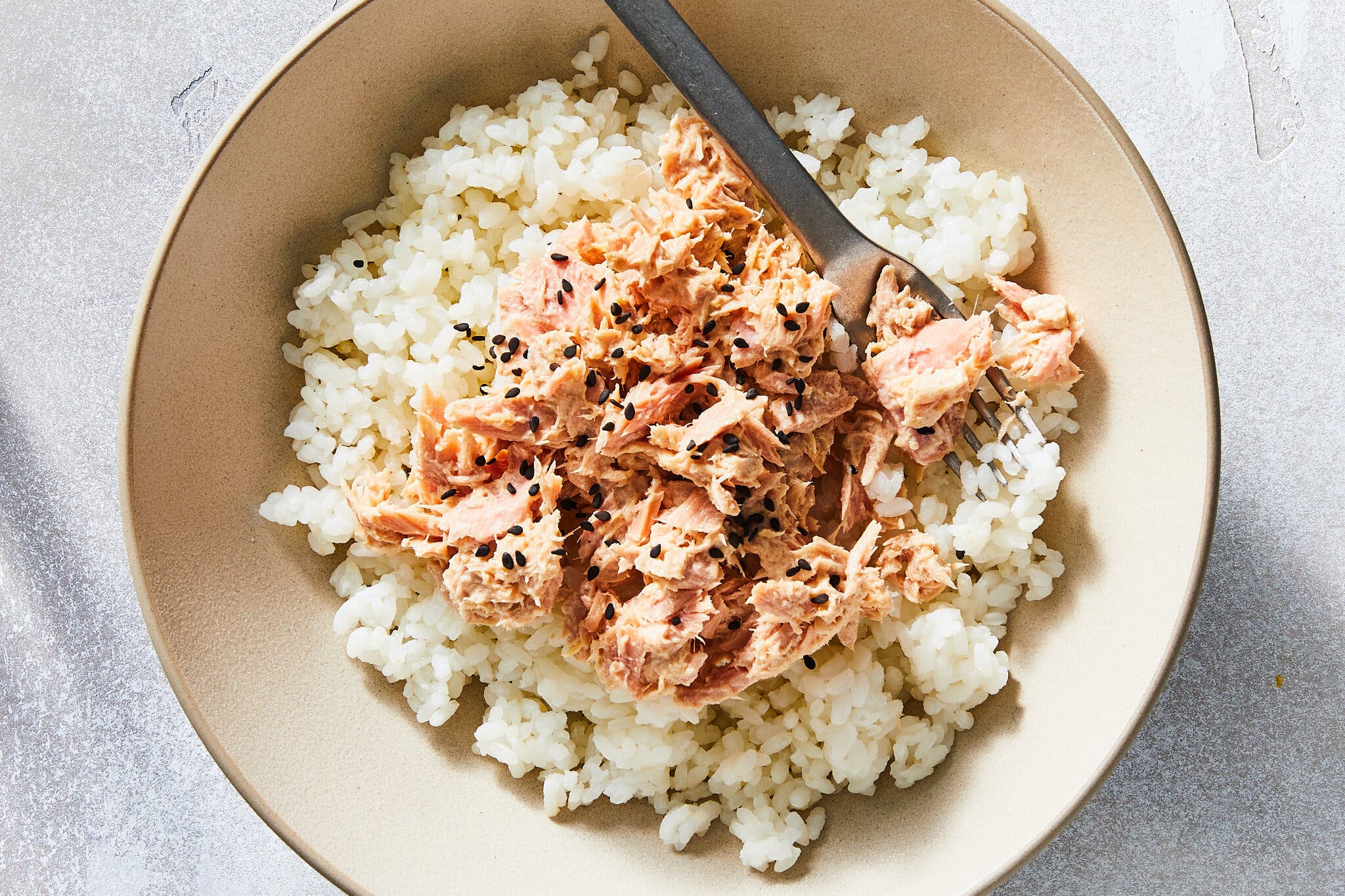An overhead image of tuna on a bed of white rice.