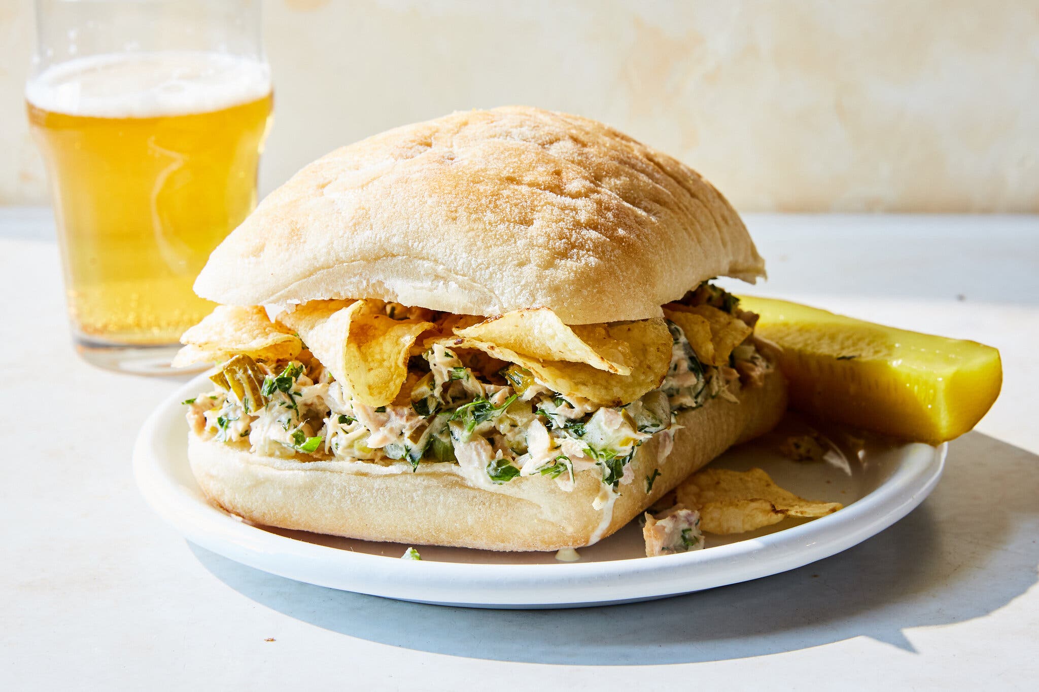 A side image of a tuna sandwich filled with potato chips.