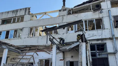 Reuters Rescue at the site of a bombed-out shell of white three-storey building which housed a bakery in Sumy, Ukraine.