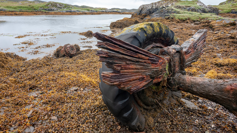 An extremely rusty truck axle with the rusted remains of a leaf spring pack still attached.