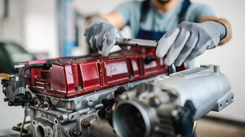 Mechanic tightens an intake manifold to an engine block.
