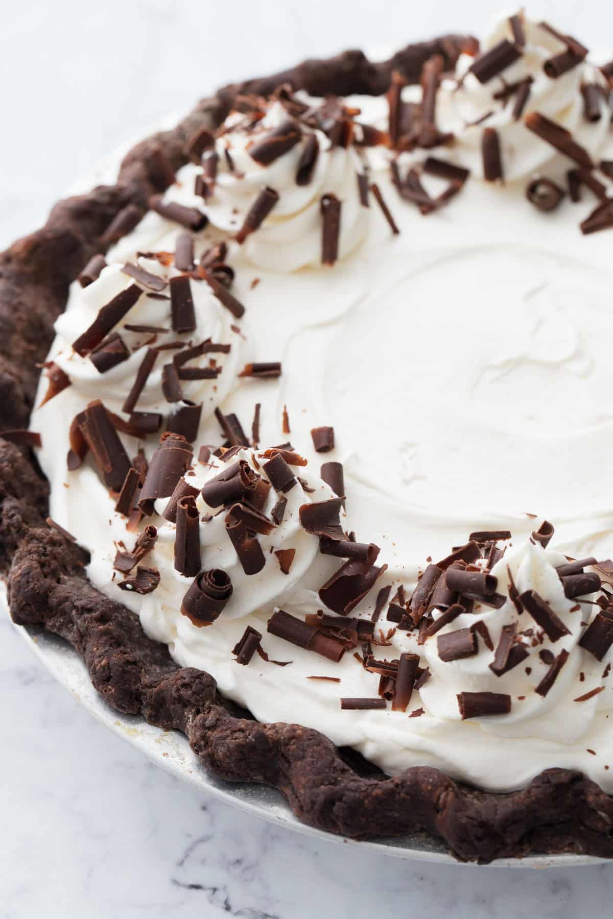 Closeup of the whipped cream topped pie, with dollops of piped whipped cream and chocolate curls.