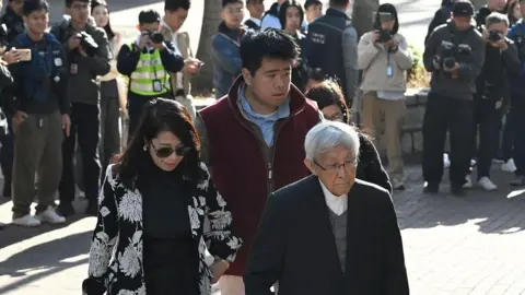 Getty Images Teresa Lai, wife of former media mogul Jimmy Lai, their son Lai Shun Yan, center, and Joseph Zen, cardinal of the Holy Roman Church, arrive at court.