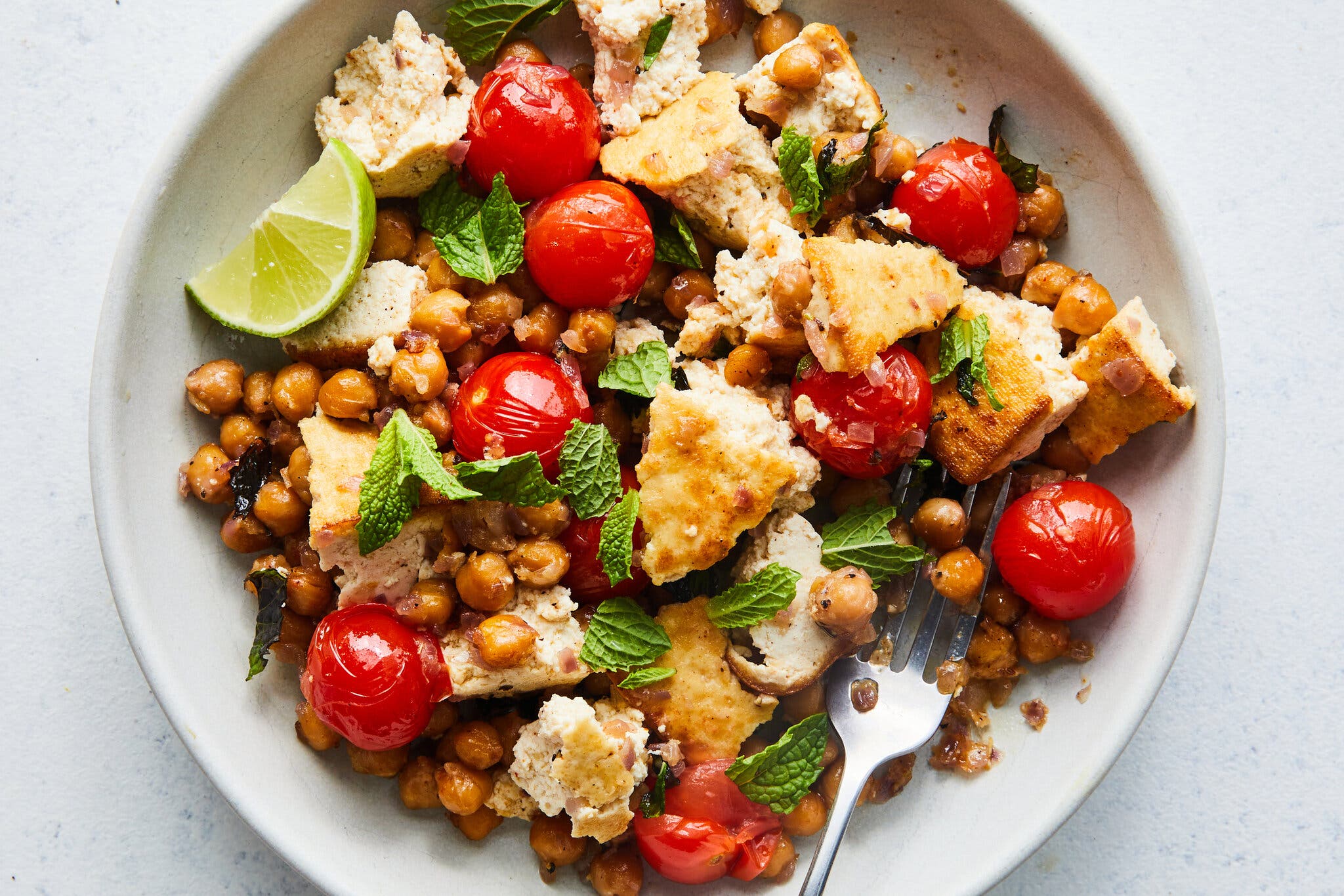 An overhead image of crumbled tofu, chickpeas, tomatoes and mint on a plate.