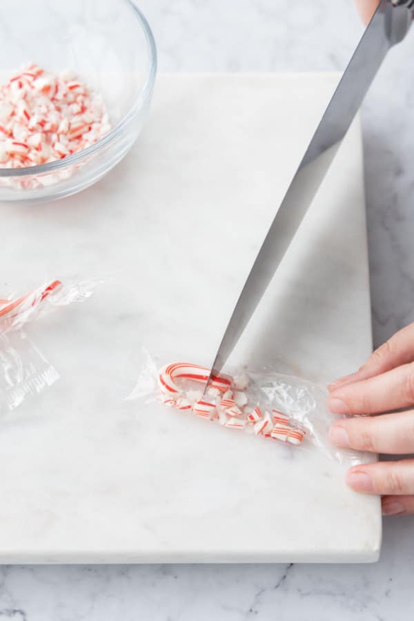 Breaking candy canes into small pieces using the dull backside of a knife.