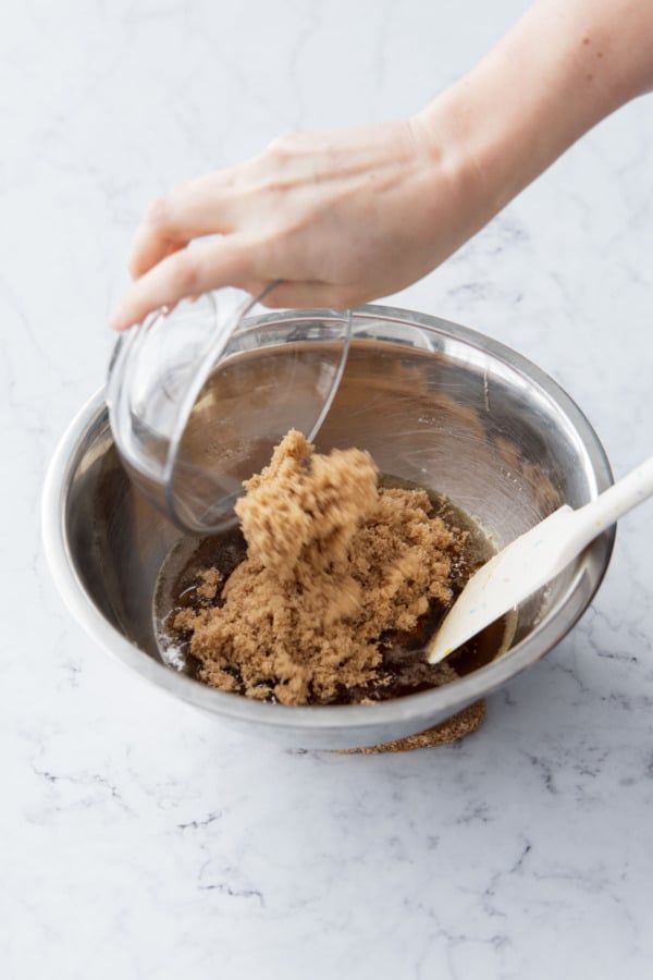 Adding brown sugar to mixing bowl along with butter and maple syrup.