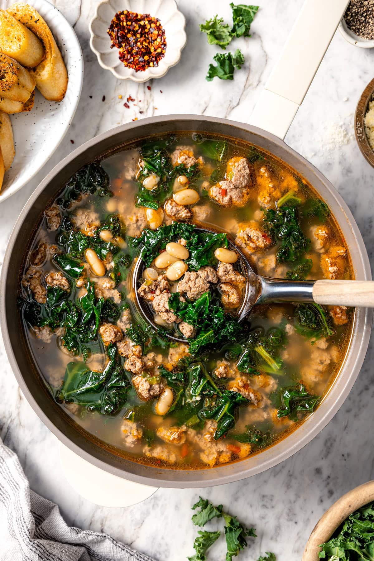 This hearty white bean soup with turkey sausage and kale is packed with protein and fiber, full of cozy flavor, and perfect for chilly days! Ladle in pot of white bean soup with sausage and kale.